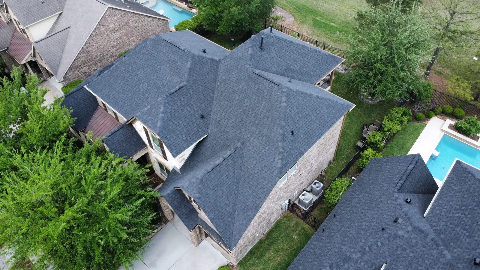 Aerial of a full roof replacement on a suburban home with a backyard pool
