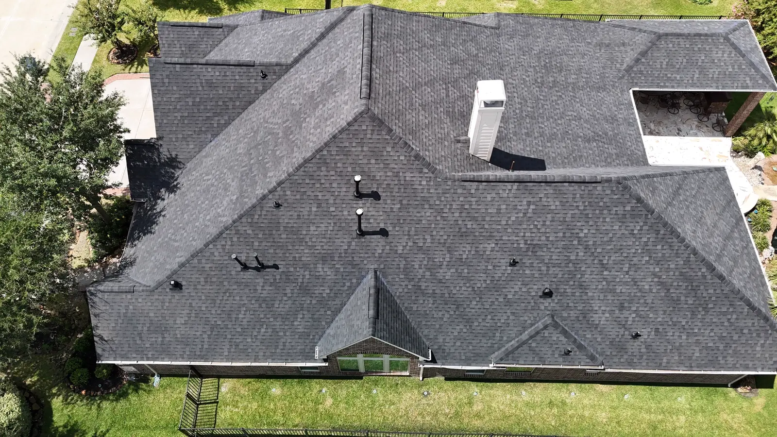 Aerial of a gray shingle roof showing eaves, gutter lines and a chimney