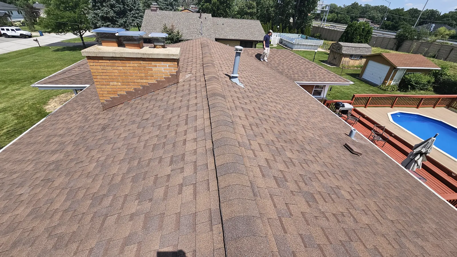 New brown architectural shingles running to the ridge past a brick chimney