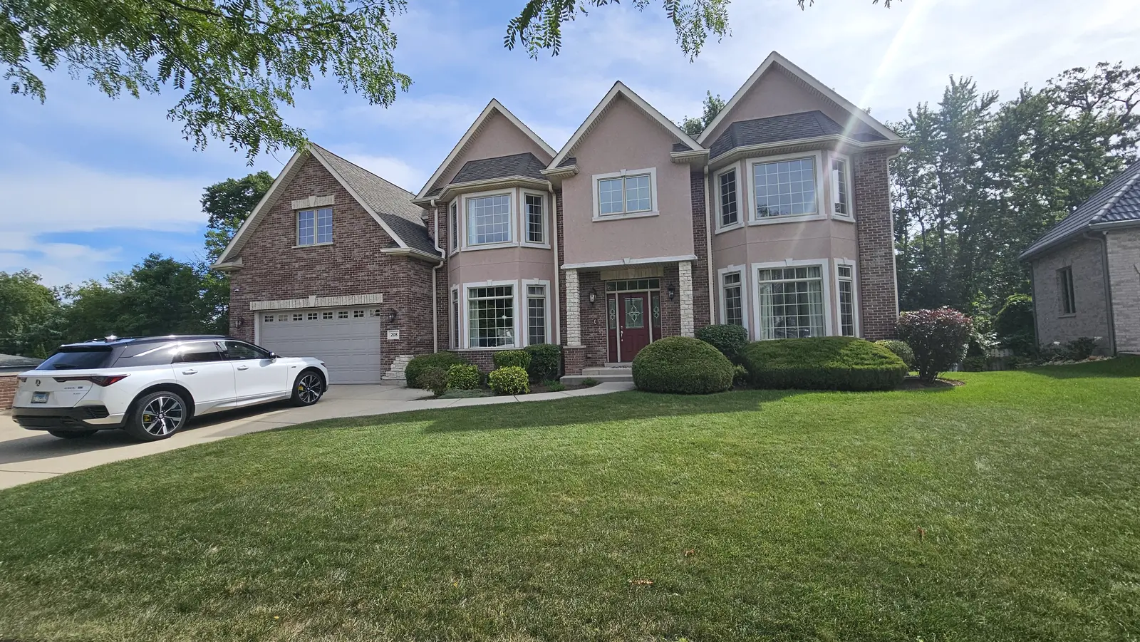 Two-story brick home with its restored roof, seen from the front lawn