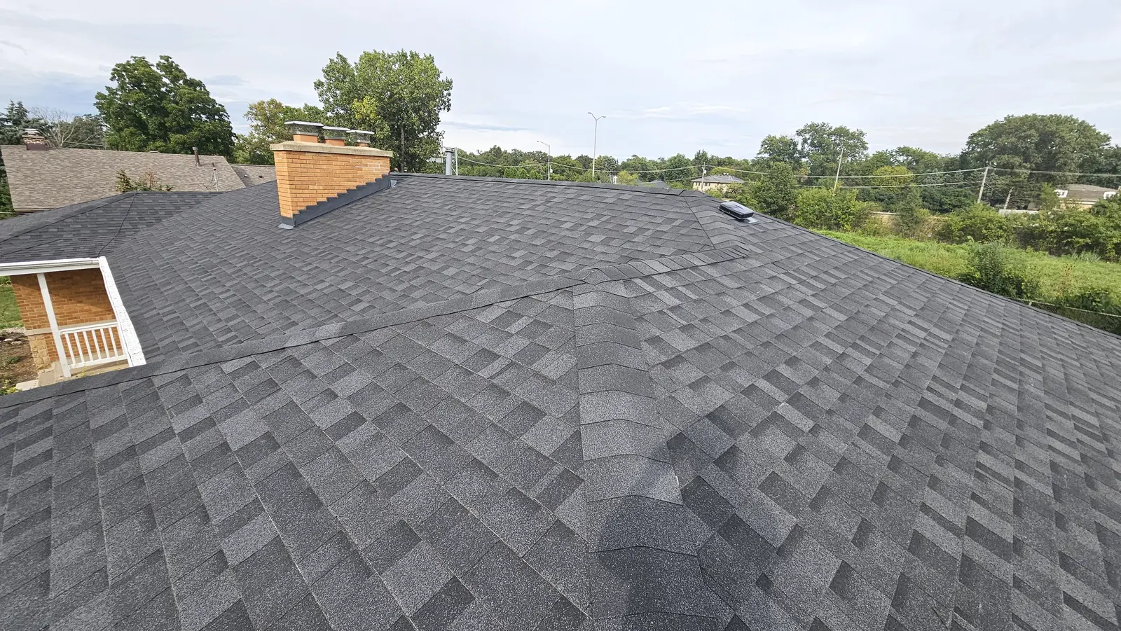 Close view of a freshly installed gray shingle roof and ridge line